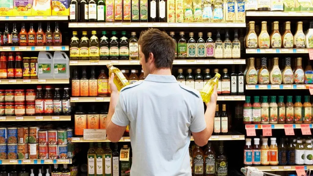 man holding bottles of oil in supermarket aisle