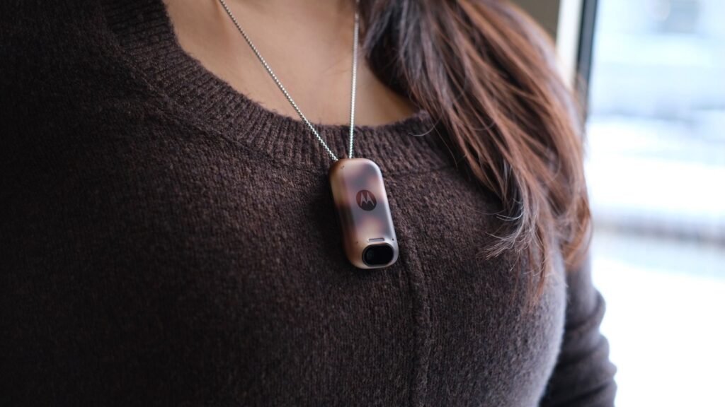 The Motorola Project Maxwell pin hanging off a necklace, worn by a woman.