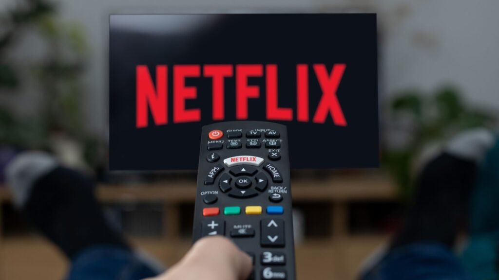 The Netflix logo on a TV, with a remote control pointed towards it